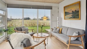 A modern living room with a large window, a sofa, chairs, a round table, and a painting on the wall. - "Fentje" - 200m from the sea by Interhome (Frørup)