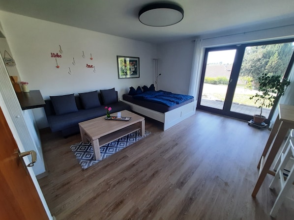 Un salon moderne avec un canapé, un lit, une table basse et une grande fenêtre.