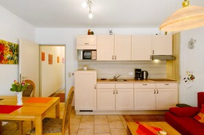 A compact kitchen with a dining area, a red sofa, and a clock on the wall.