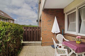 A patio with a table and chairs, a wooden fence, and a brick wall.