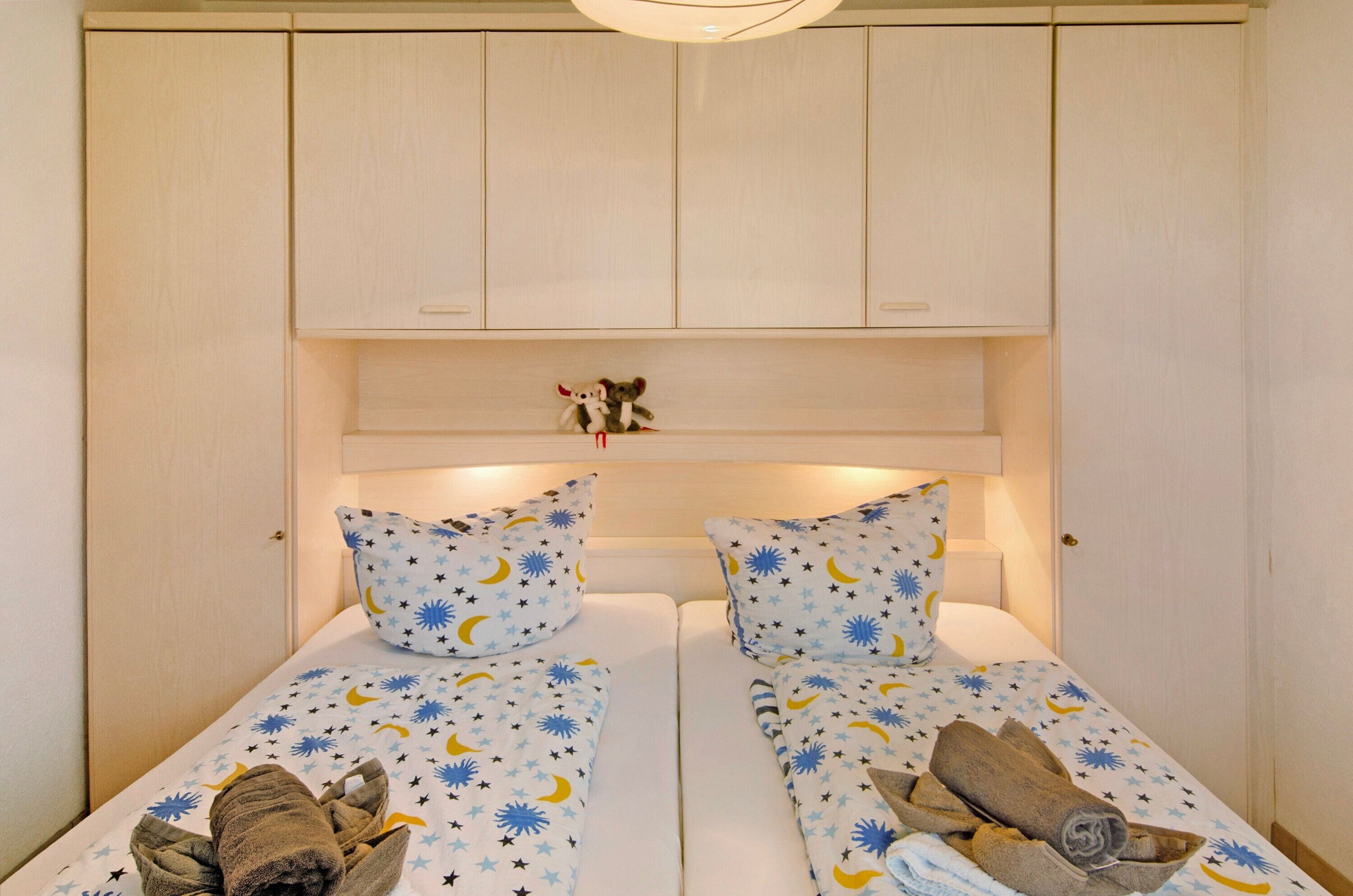 Ein Doppelbett mit Himmelsdecke, ein Nachttisch mit Lampe und ein kleines Regal mit einem Stofftier.