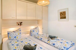 A bedroom with two beds, a nightstand, a wall-mounted lamp, and a framed picture.