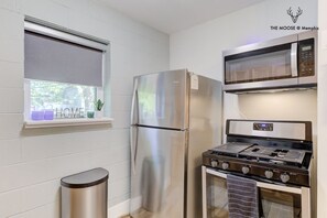 A compact kitchen with a stainless steel refrigerator, a microwave, and a gas stove.