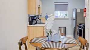 A compact kitchen with wooden cabinets, a coffee machine, a refrigerator, and a window with a view. - Luxe Modern loft w/ King Bed, Free Parking & Wi-Fi (Memphis)