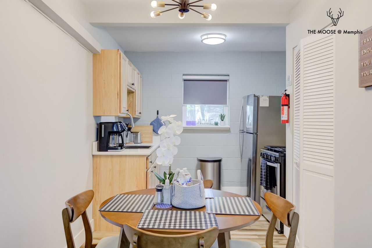 A compact kitchen with a dining area, a refrigerator, a coffee machine, and a window with a view.