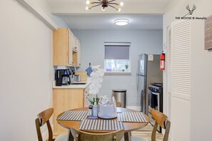 A compact kitchen with a dining area, a refrigerator, a coffee machine, and a window with a view.