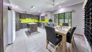 Una cocina moderna con una isla central, un comedor con mesa y sillas, y un amplio ventanal que ofrece vistas al exterior.