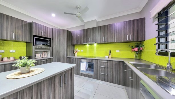 Una cocina moderna con gabinetes grises, salpicadero verde y pileta de acero inoxidable.