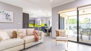 Una sala de estar moderna con un sofá, una silla y una zona de comedor con mesa y sillas.