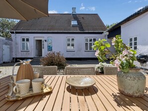 Un patio con mobiliario exterior, una mesa y una parrilla.