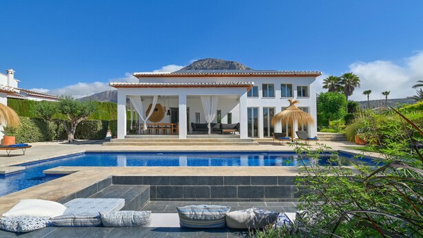 A modern house with a swimming pool, outdoor seating, and a mountain view.