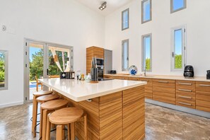 Een moderne keuken met een centraal eiland, barkrukken en uitzicht op de omgeving.