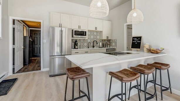 A modern kitchen with white cabinets, stainless steel appliances, and a central island with stools.