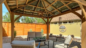 A covered patio area with outdoor furniture, a wooden fence, and a decorative wall.