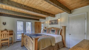 A rustic bedroom with a wooden bed, a wooden dresser, and a door. - Riverfront Fire Pit, Gas Stove, Near Skiing, Hot Springs, & Hiking Adventures! (Pagosa Springs)