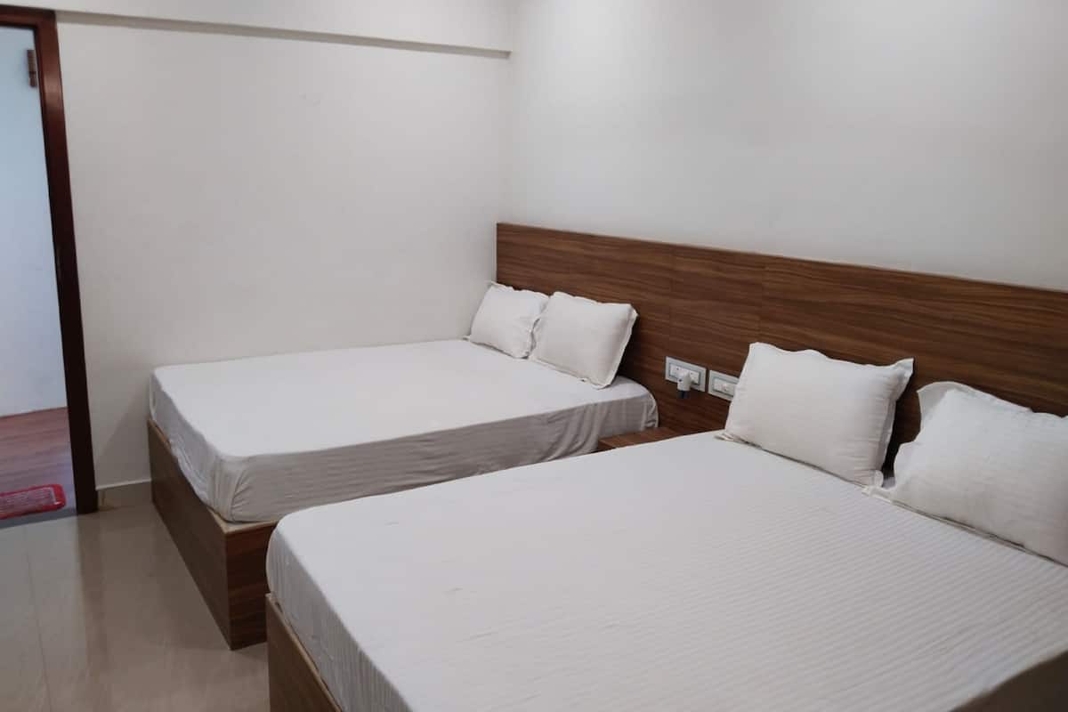 A hotel room with two single beds, each with a wooden headboard and white bedding.