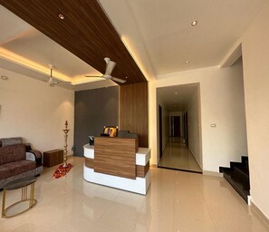 A modern living room with a sofa, a coffee table, a decorative lamp, and a wooden accent wall. - Sri Krishna Residency (Tiruchirappalli)