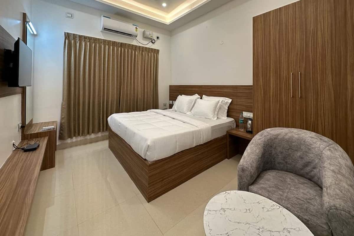 A modern hotel room with a wooden bed, a flat-screen TV, a desk, and a chair.