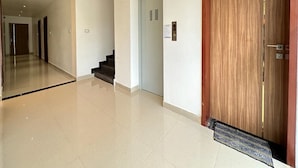 Un pasillo amplio con puerta de madera, escalera y ascensor.