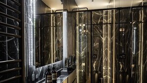 A modern bathroom with a glass-enclosed shower, a marble vanity, and a large mirror.