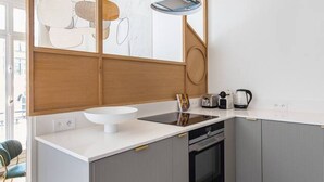 A modern kitchen with a large island, built-in oven, and a pendant light.