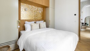 A bedroom with a large bed, wooden headboard, and a decorative wall panel.