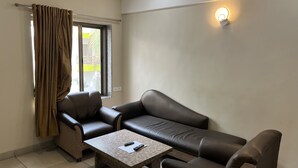 A modern living room with a sofa, armchair, and coffee table. - Ruturaj Inn (Alibag)