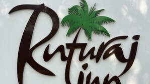 A sign with the name "Ritwaj Inn" and a palm tree graphic. - Ruturaj Inn (Alibag)