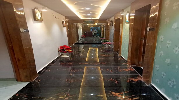 A hotel hallway with a reflective black marble floor, wooden doors, and floral wallpaper.