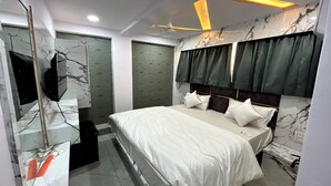 A modern bedroom with a large bed, a ceiling fan, and a TV mounted on the wall.