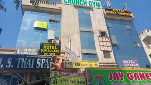 A building with multiple signs, including 'CRUNCH GYM', 'HOTEL BHAVY MANSION', and 'HOTEL SUN SQUARE'.