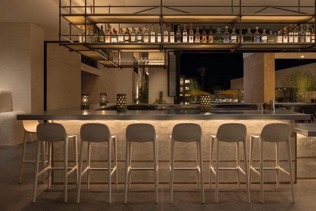 Sip crafted drinks at the glowing bar beneath bottle displays.