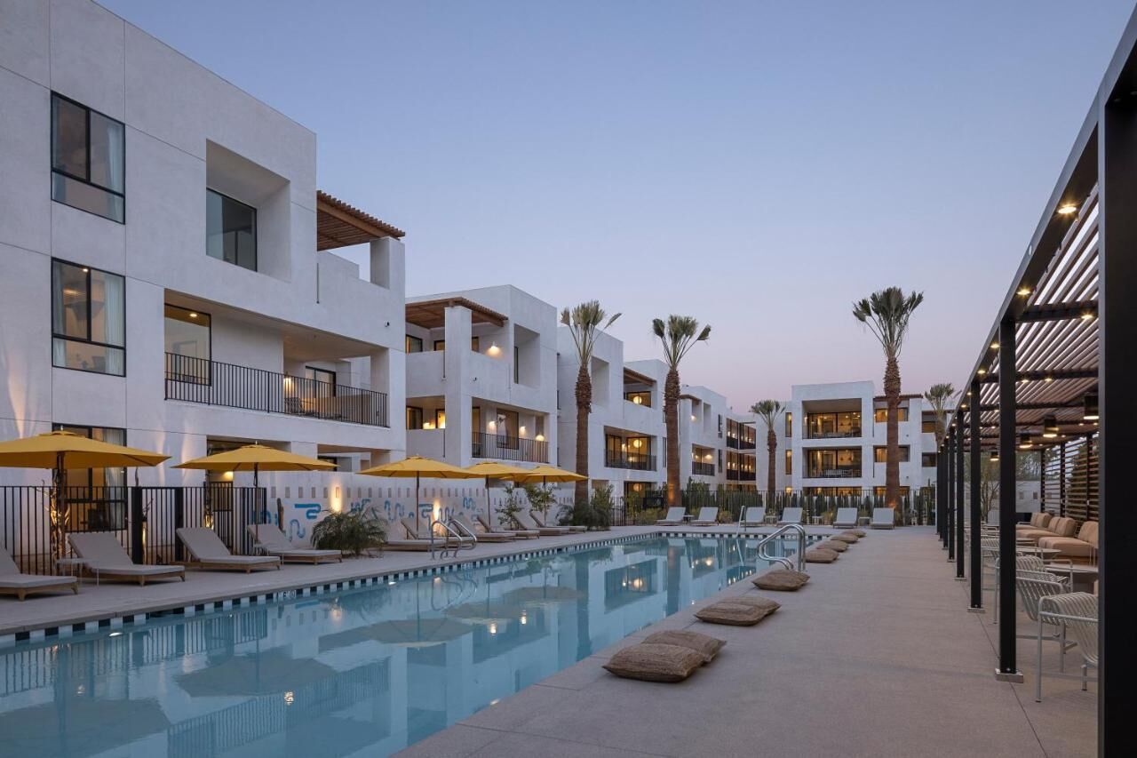 A modern hotel with a pool, sun loungers, and outdoor seating.