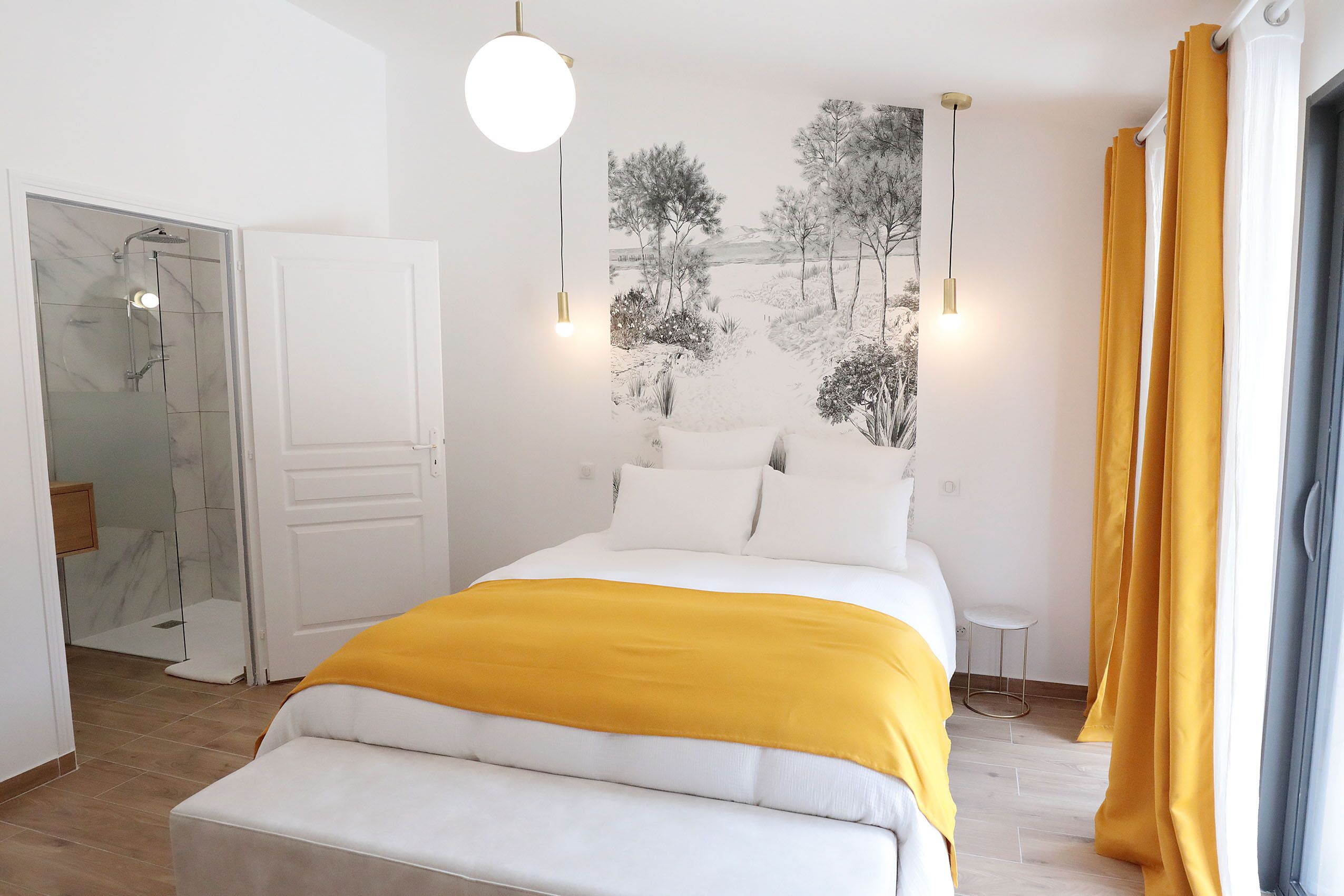 A modern bedroom with a large bed, a glass shower enclosure, and a view of the outdoors.