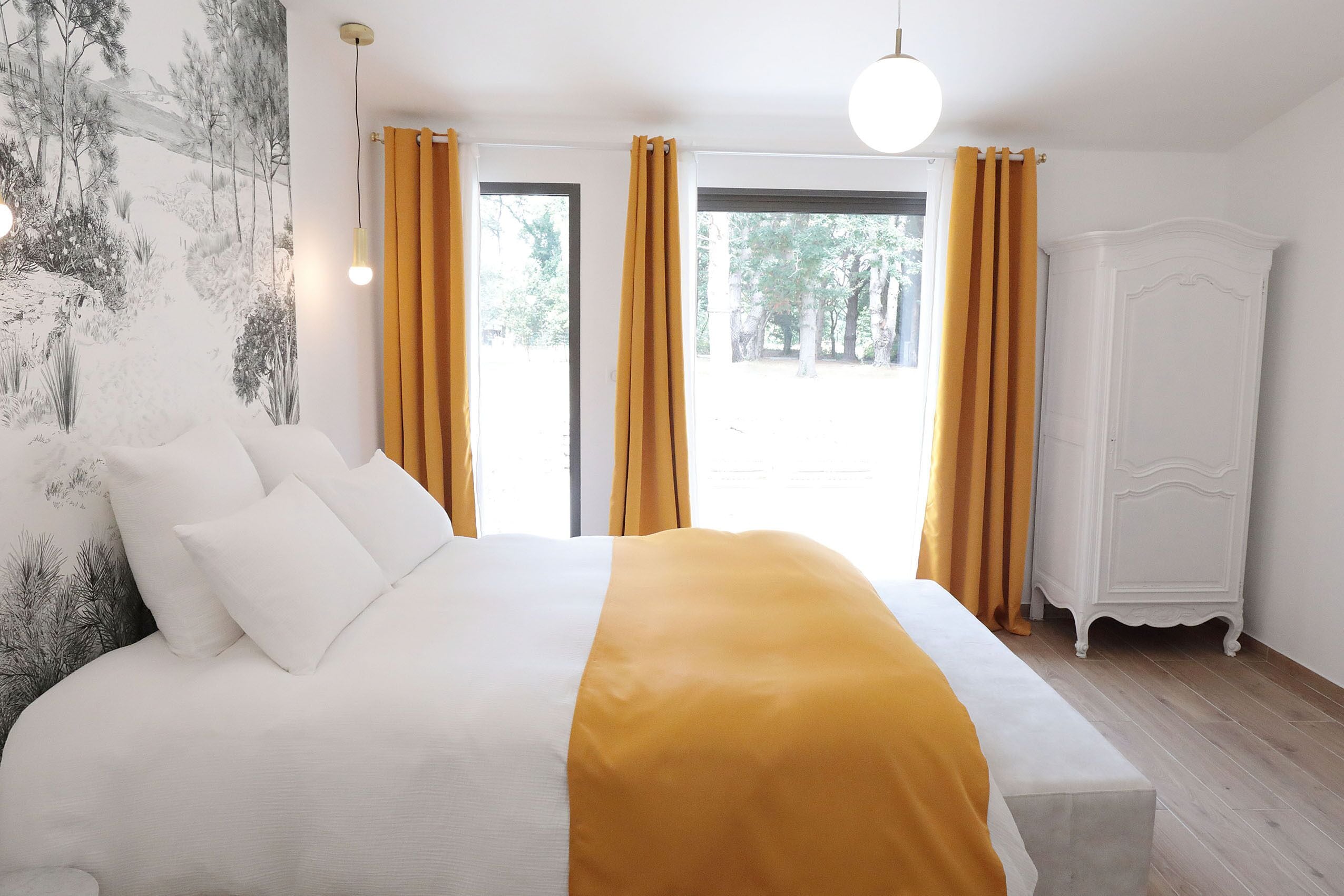 Un dormitorio con una cama grande, un armario blanco y vistas al exterior.