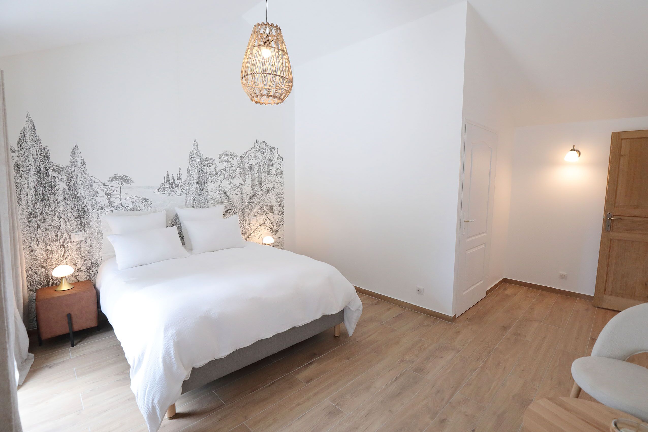 Een slaapkamer met een bed, nachtlampjes, een hanglamp en een muurschildering.
