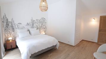 Een slaapkamer met een bed, nachtlampjes, een hanglamp en een muurschildering.