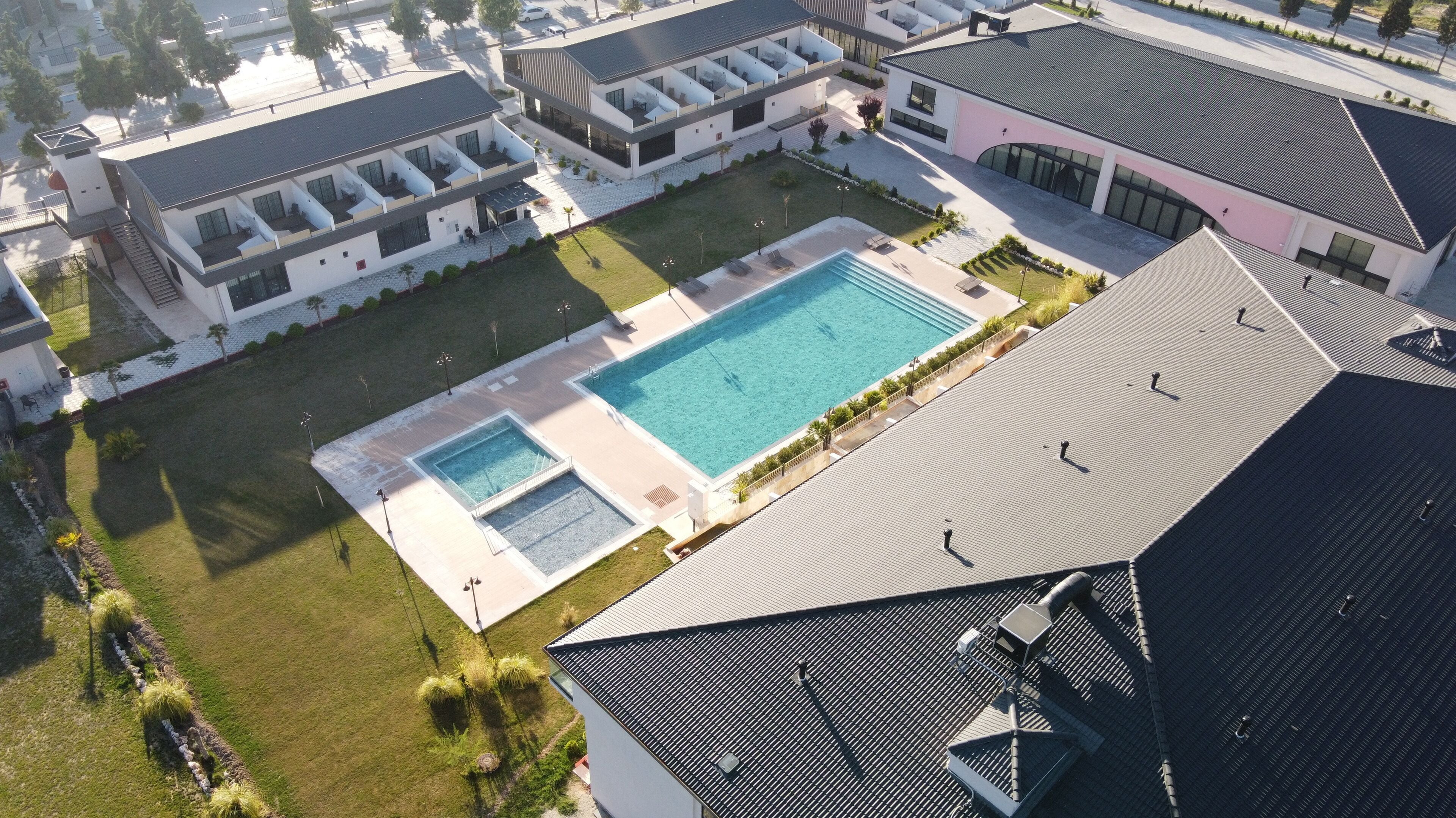 Vue aérienne d’un complexe immobilier moderne doté d’une piscine centrale, de nombreux balcons et d’une pelouse bien entretenue.