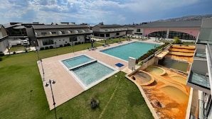 Un hotel moderno con una grande piscina all'aperto, un'area benessere e un prato curato.