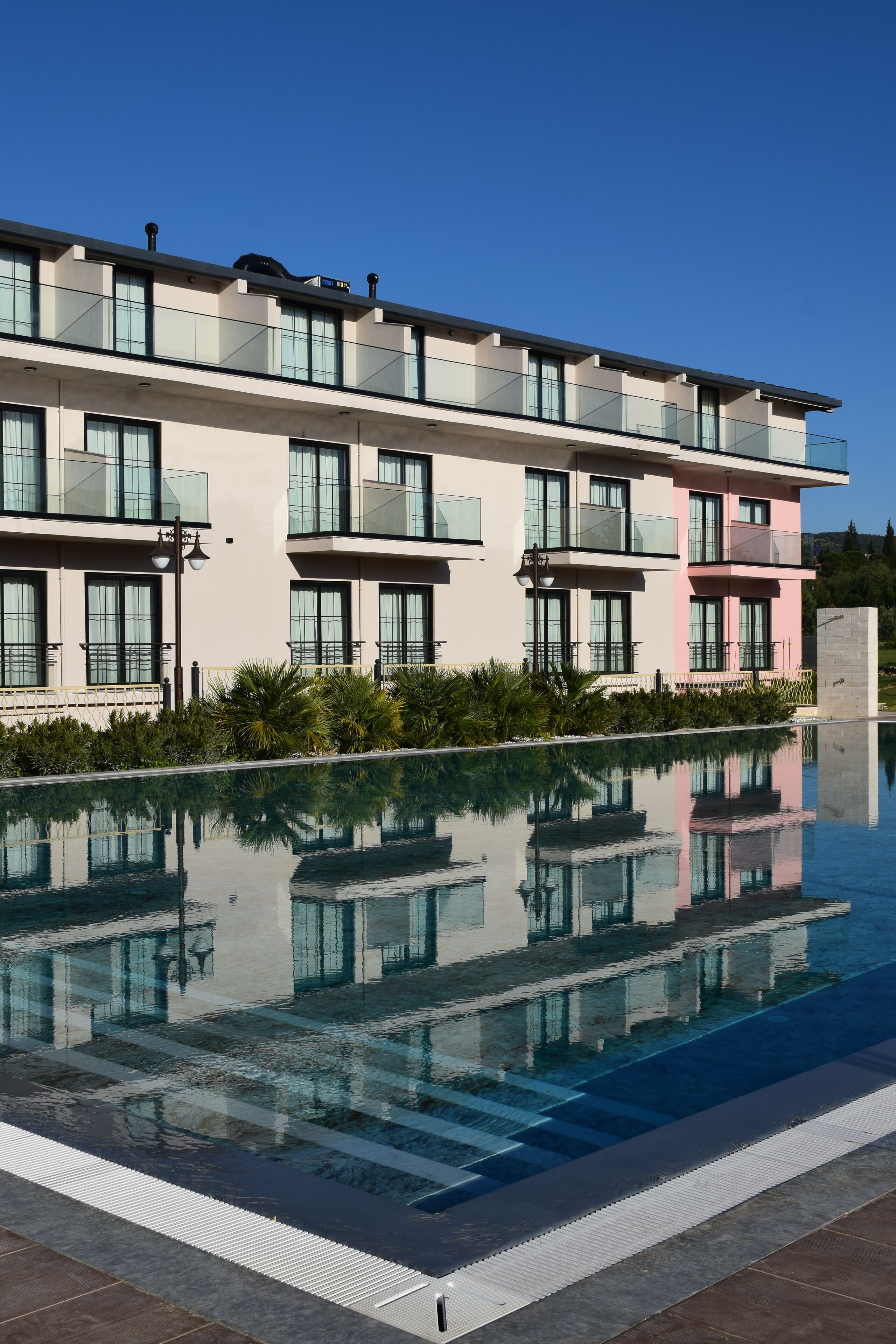 A modern hotel with a swimming pool, large windows, and a flat roof.