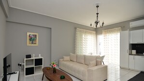 Un salon moderne comprenant un canapé, une table basse, un téléviseur et un coin cuisine.