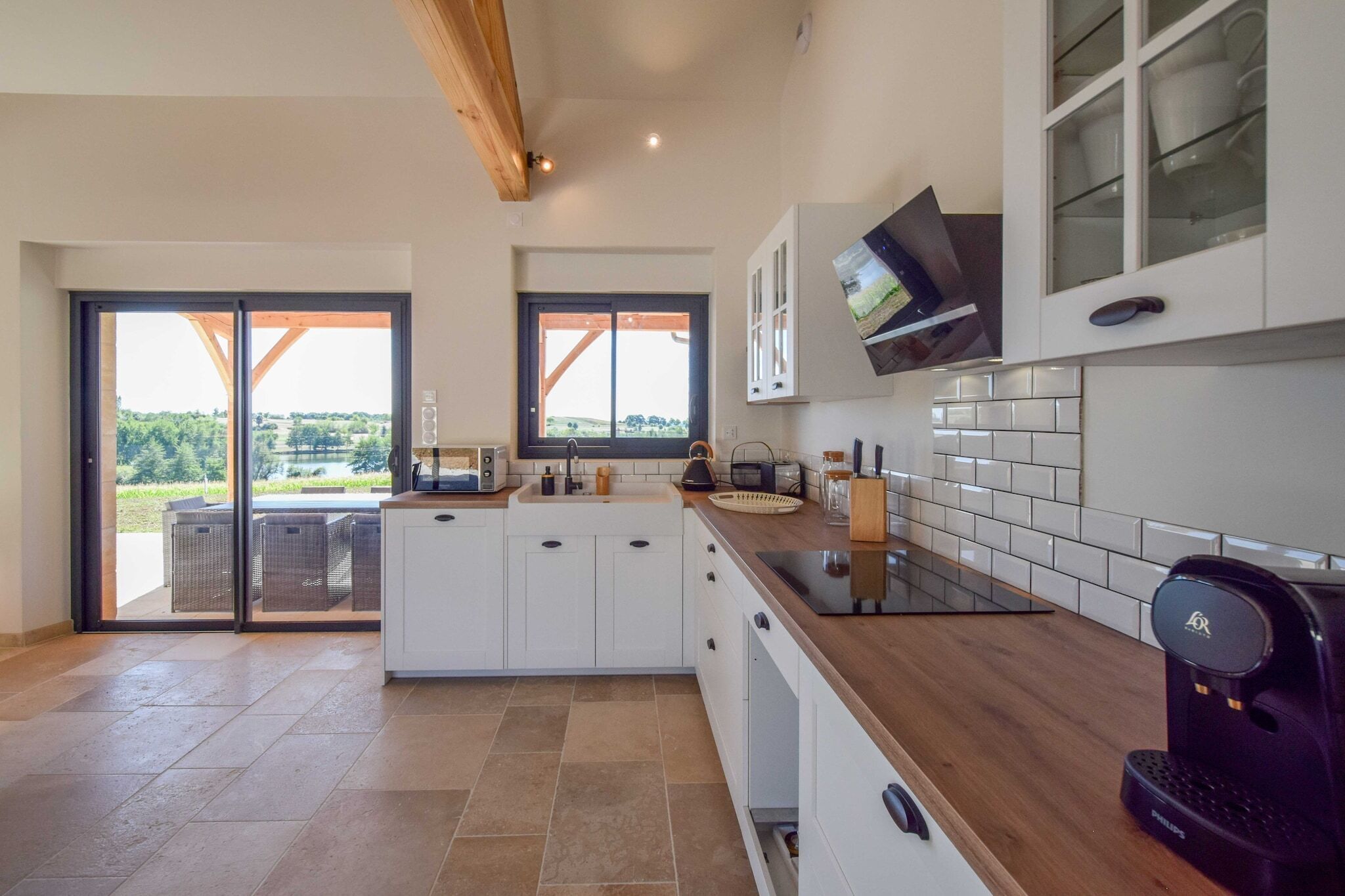 Una cocina moderna con armarios blancos, encimera de madera y una cafetera.