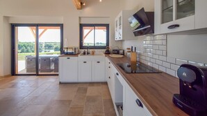 Une cuisine moderne avec des meubles blancs, un plan de travail en bois et une machine à café.