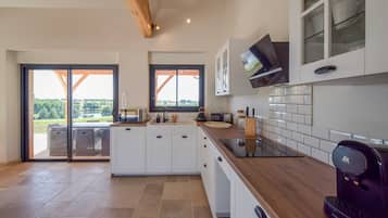 Una cocina moderna con armarios blancos, encimera de madera y una cafetera.