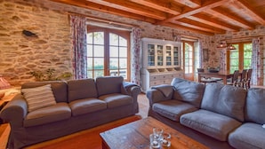Ein rustikaler Raum mit Steinwänden, Holzbalken und zwei grauen Sofas.