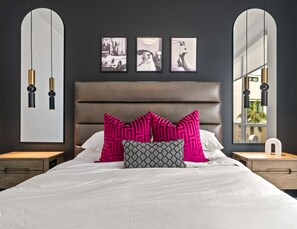A modern bedroom with a large bed, two nightstands, a headboard, and three framed pictures on the wall.