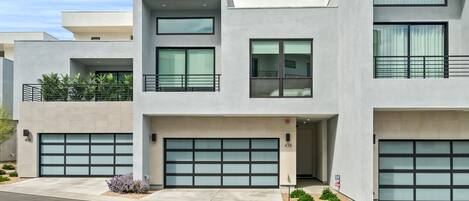 Uma casa moderna com dois andares, garagem, varanda e um pequeno jardim.