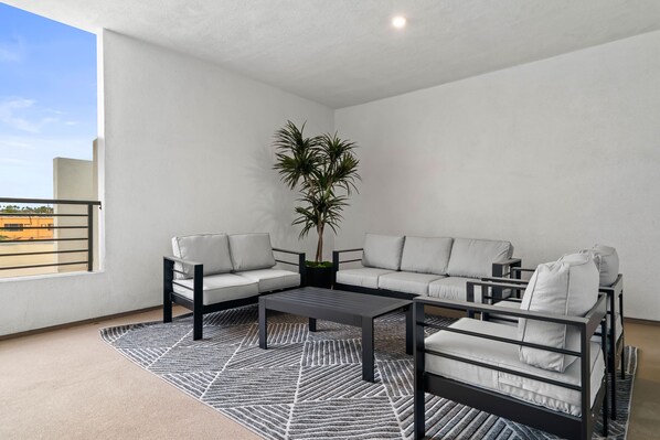 Een moderne woonkamer met een hoekbank, een salontafel en een potplant.