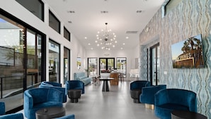 A spacious lobby with blue velvet sofas, a central coffee table, and a patterned wall.