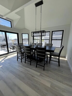 A dining area with a table and chairs, large windows, and a view of the outside.